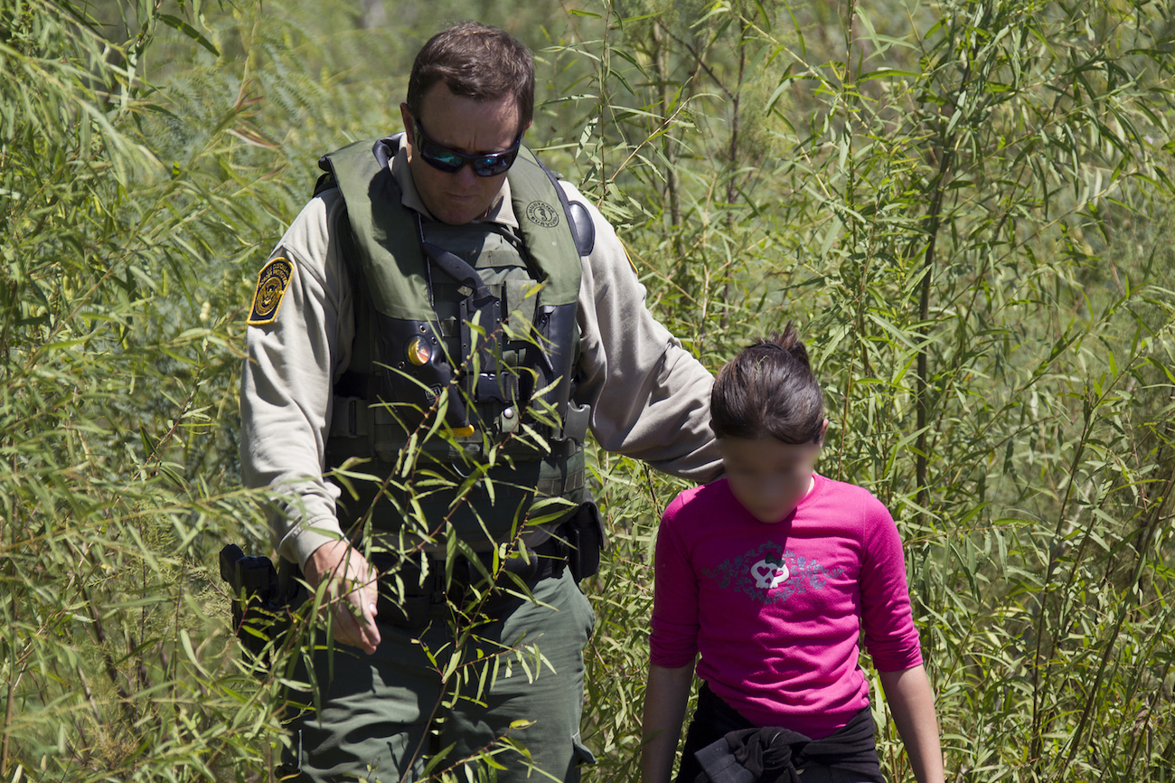 A Border Patrol officer assists a girl stranded on the river bank of Rio Grande in Texas. Photo by Donna Burton/US Customs and Border Patrol.